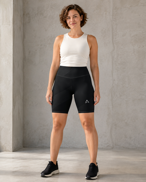 Self Made Club Contour Biker Short in black on a female model, showing high waistband, subtle diagonal stripe bands and left thigh mark. AI-generated styling visualization.