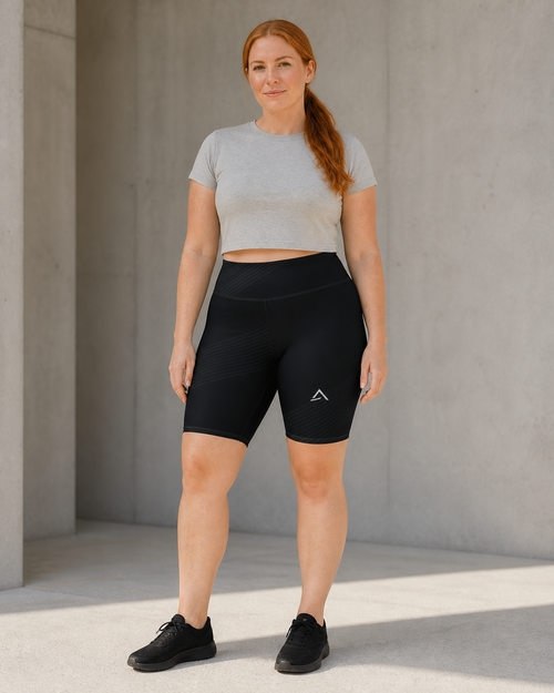 Self Made Club Contour Biker Short in black on a different female model, showing high waistband, subtle diagonal stripe bands and left thigh mark. AI-generated styling visualization.