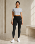 Self Made Club Form Legging in black on a female model in front view, showing cross-front waistband, left thigh mark and full-length fit. AI-generated styling visualization.
